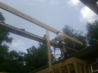 Carpenter setting a ridge beam over a new addition frame — Ice Dam Removal by Roofing Brothers in Ruthville