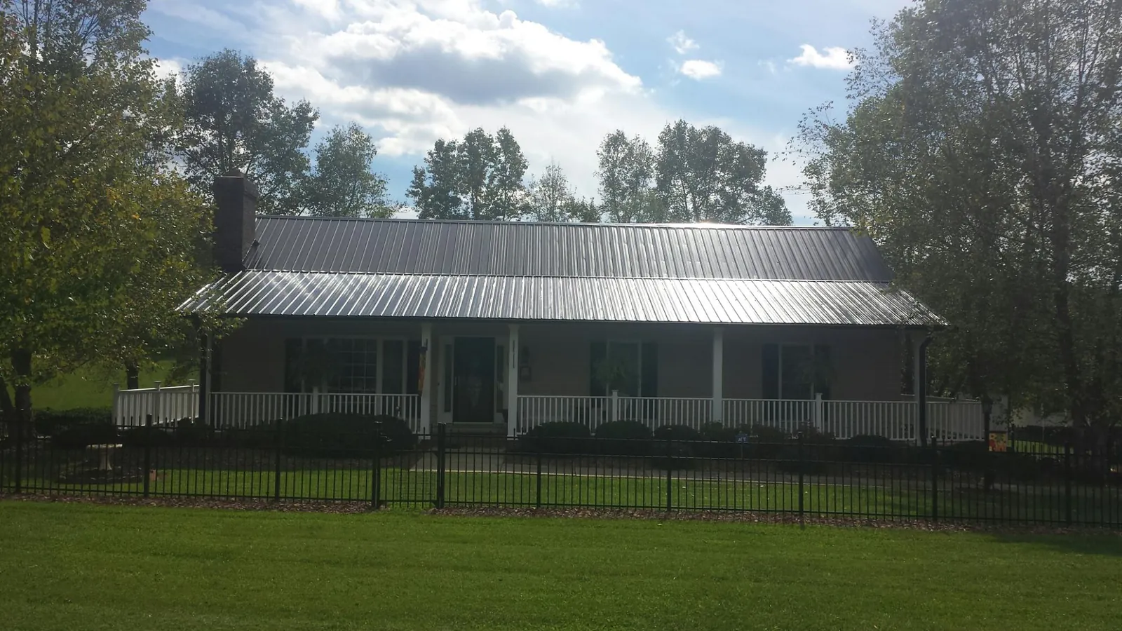 Gray metal roof on a brick ranch with a full width front porch — Gutter Guard Installation work by our crew in Ruthville