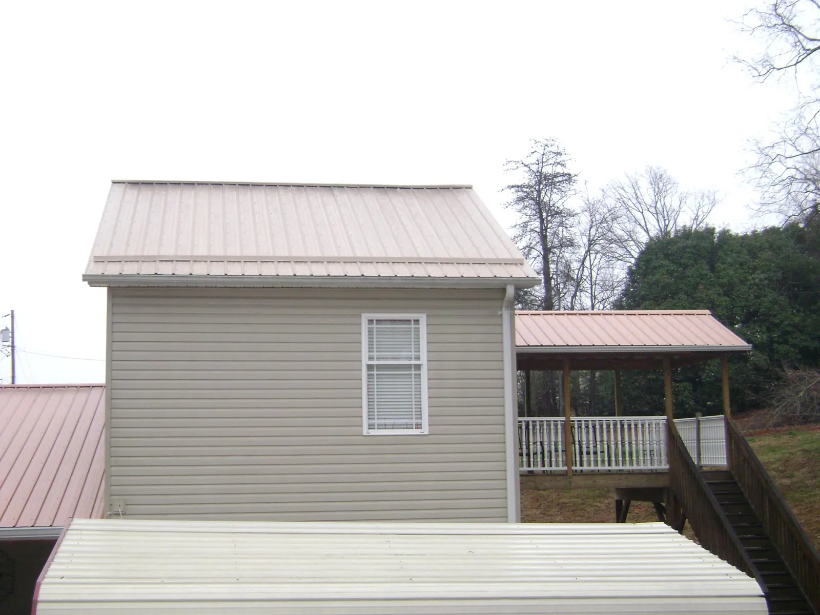 Tan metal roofs on a two story addition and attached porch, from a Roof Replacement job in Ruthville